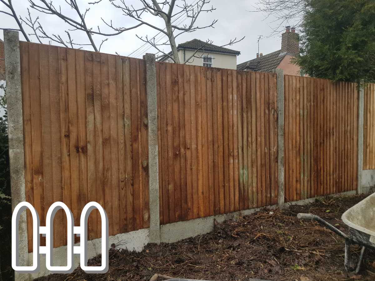New wooden fence installation with concrete posts in a residential garden with a barrow and bare trees in the background