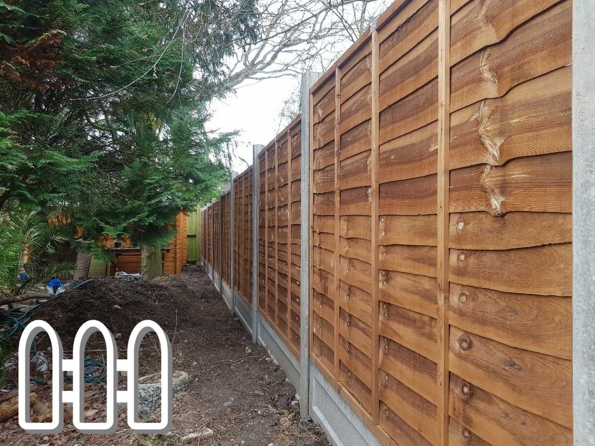 Beautifully constructed wooden fence in a backyard garden, featuring rich brown panels with horizontal alignment, lined along a narrow path surrounded by lush green trees and shrubs.