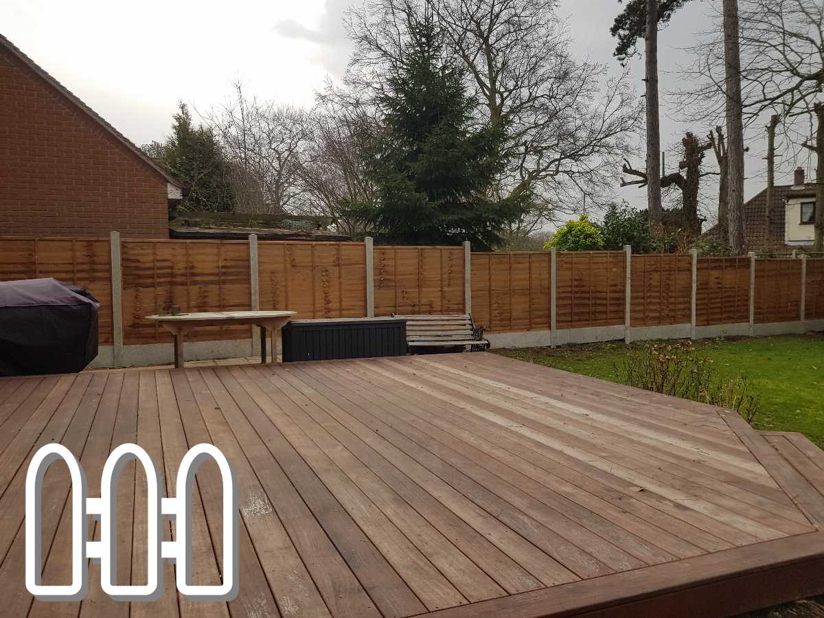 Spacious backyard with a new wooden fence and a large decking area, surrounded by mature trees and a tidy lawn.