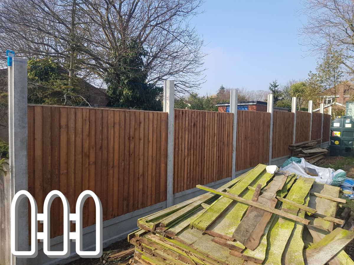 Newly installed wooden fence panels in a residential backyard with old, disassembled fence pieces in the foreground and trees in the background.