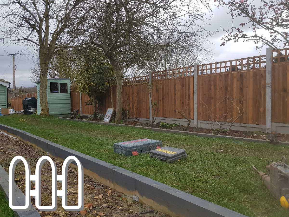 Newly installed wooden fencing in a residential backyard featuring fresh landscaping and a green garden shed