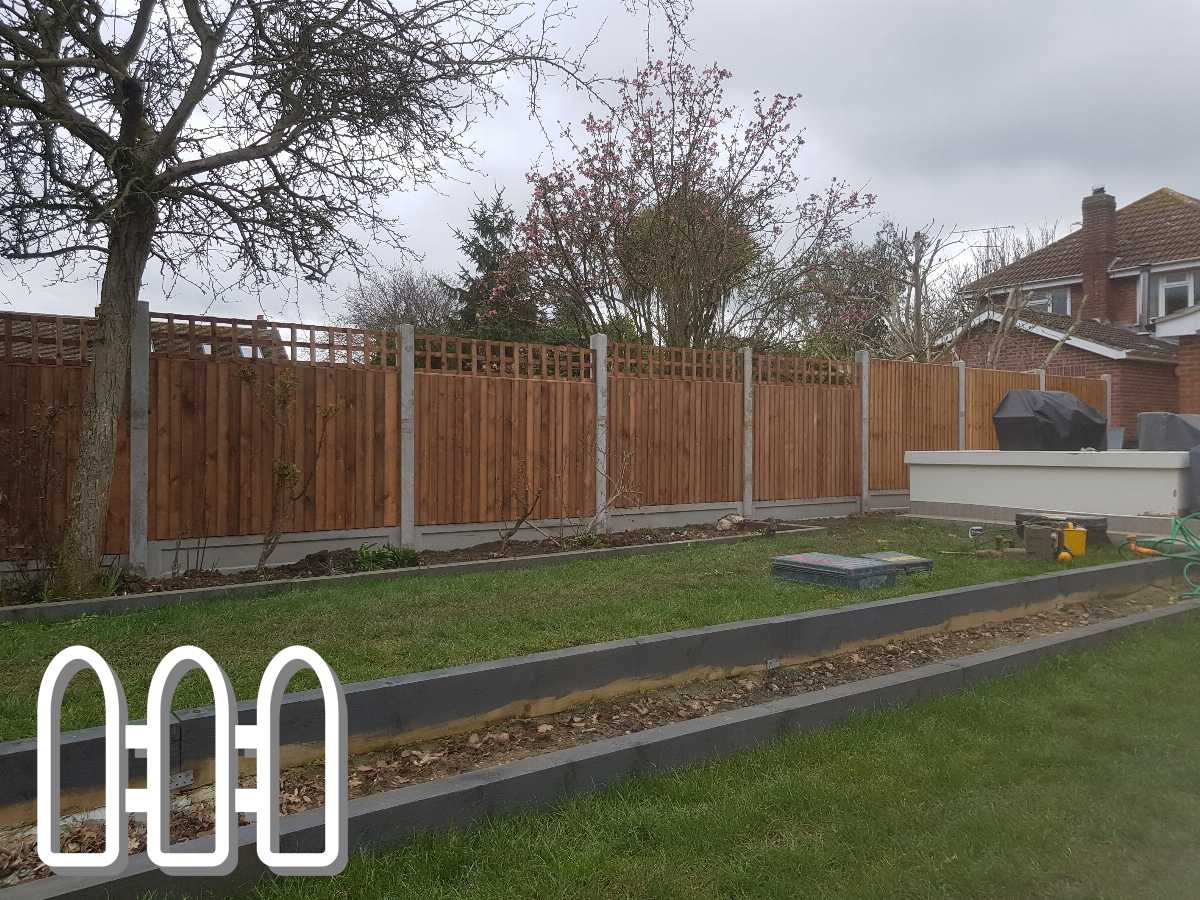 New wooden fence with lattice top installed in a residential backyard, featuring green lawn and budding trees, enhancing the property's privacy and aesthetic appeal.