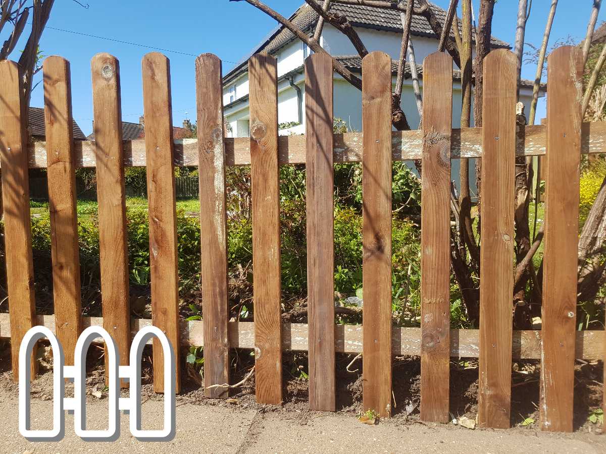 Sturdy wooden fence with vertical planks in a sunny garden, demonstrating quality outdoor carpentry.