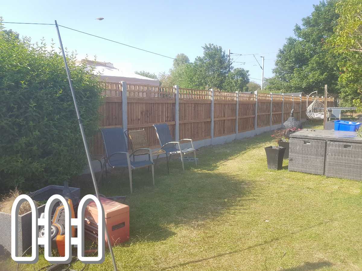 Sunny backyard with newly installed wooden fence, complete with outdoor furniture and gardening tools scattered around