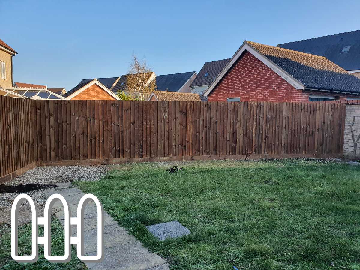 Well-maintained wooden fence in a residential backyard with a green lawn and brick houses in the background