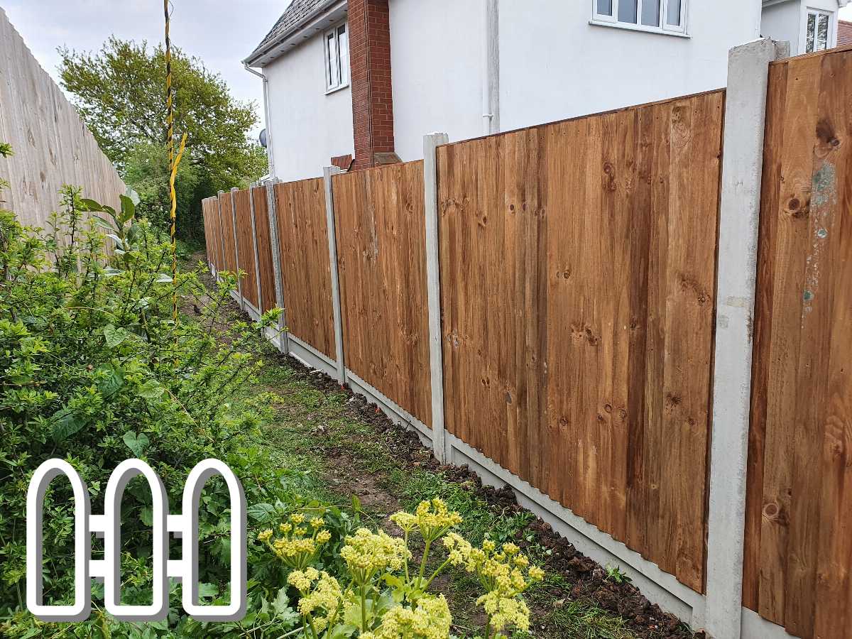 Newly installed wooden fence panels alongside a residential home, featuring a lush garden border with greenery and yellow flowers.